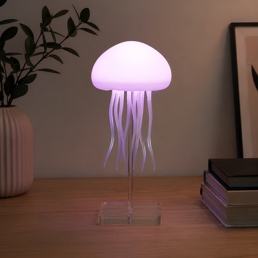 A jellyfish-shaped table lamp with a glowing purple-white dome and translucent tentacles on a clear acrylic stand, placed on a wooden tabletop with a vase and books in the background.